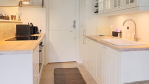 A modern kitchen with white cabinets, a built-in microwave, and a stainless steel sink. - 4 Person Holiday Home in Gilleleje (Gilleleje)