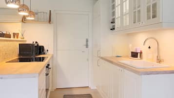 A modern kitchen with white cabinets, a built-in microwave, and a stainless steel sink.