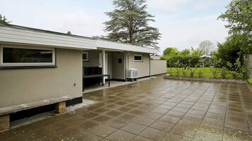 A building with a covered patio area, a bench, and a small table.