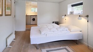 A bedroom with a bed, a radiator, a washing machine, and a window. - 4 Person Holiday Home in Gilleleje (Gilleleje)