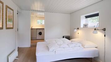 A bedroom with a bed, a radiator, a washing machine, and a window.