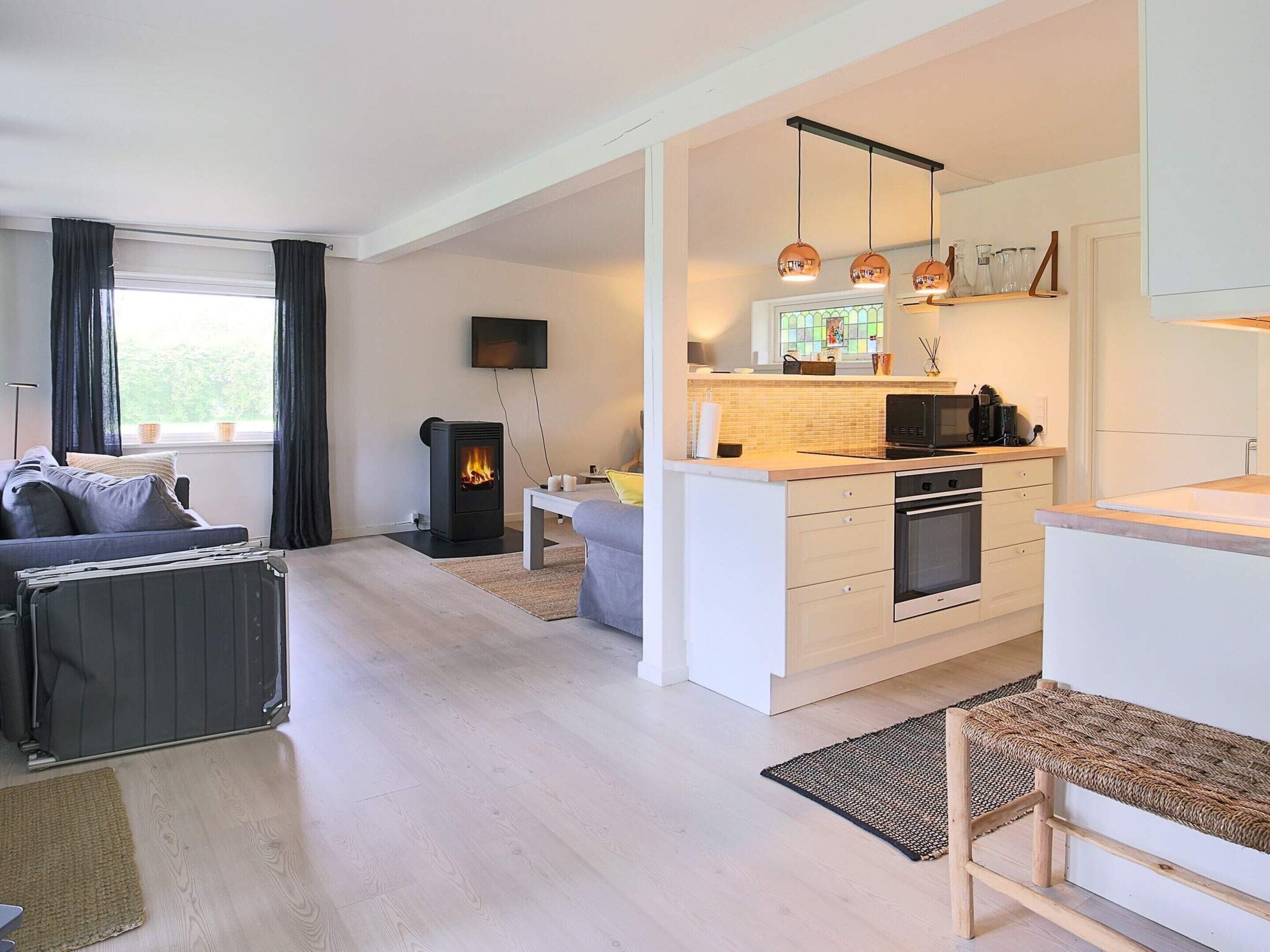 A modern living room with a sofa, a fireplace, and a kitchen area with a microwave and oven.