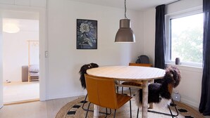 A dining area with a round table, chairs, a hanging light fixture, and a window with curtains. - 4 Person Holiday Home in Gilleleje (Gilleleje)