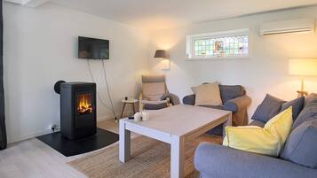 A cozy living room with a fireplace, a sofa, a coffee table, and a TV mounted on the wall.