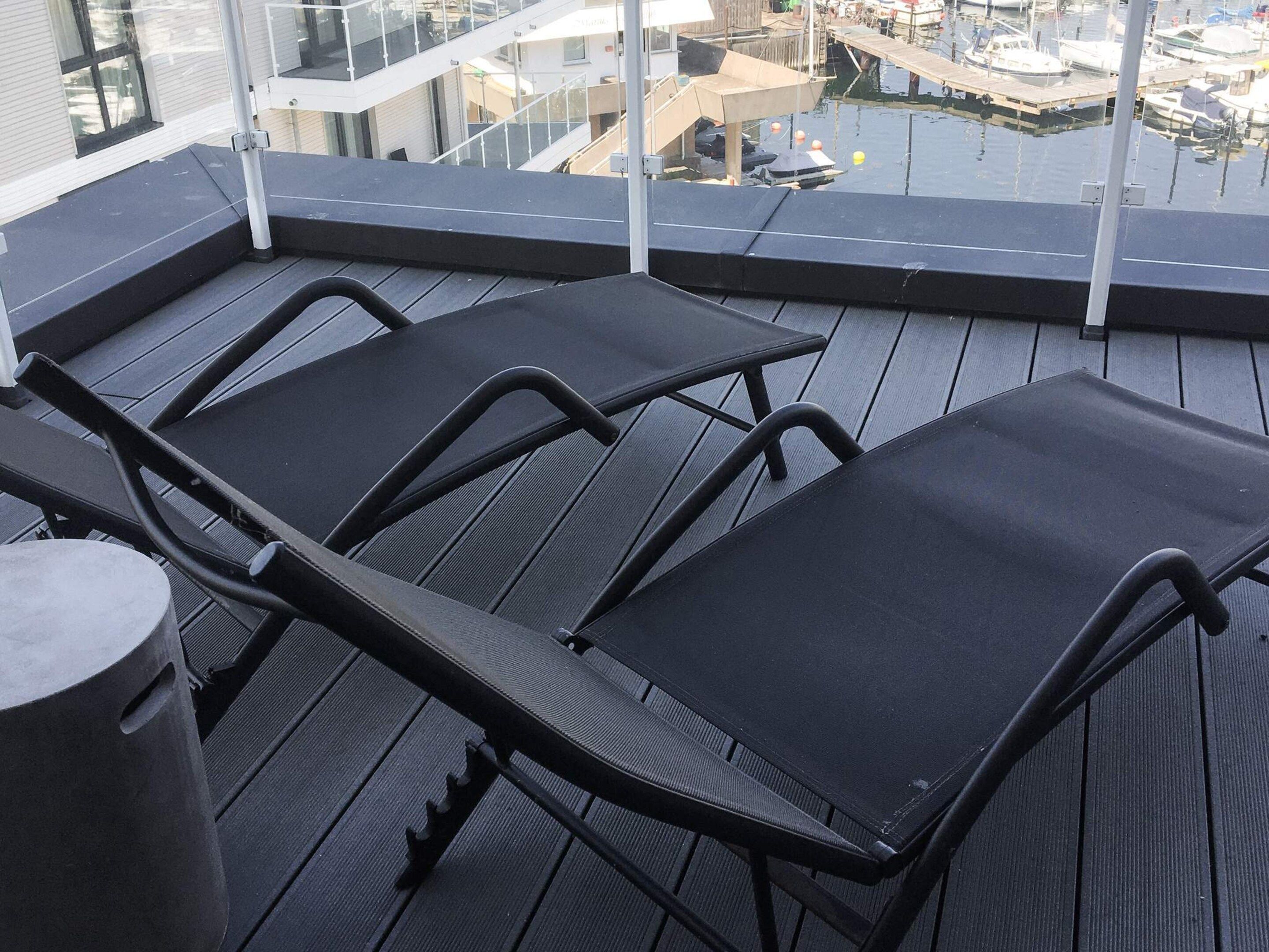 A balcony with black lounge chairs and a small round table.