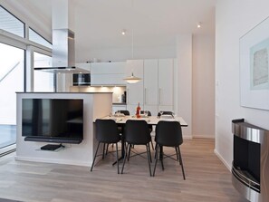 A modern kitchen with a dining area, a flat-screen TV, and a built-in fireplace.