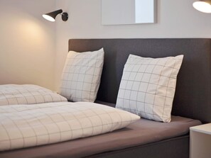 A bed with a headboard, two pillows, and a bedside table.