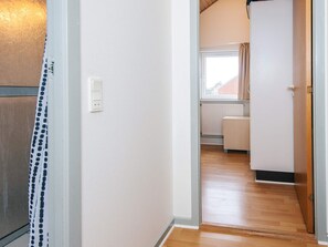 Un couloir avec une porte blanche, une prise de courant et une fenêtre avec des rideaux.