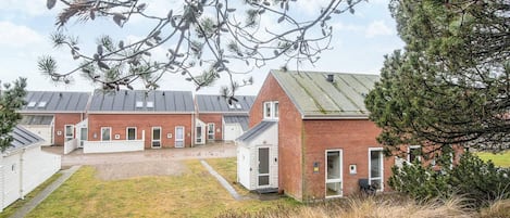 A row of brick buildings with a gravel driveway and a grassy area in front.