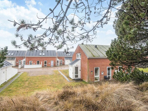 A row of brick buildings with a gravel driveway and a grassy area in front.