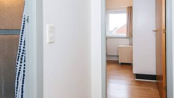 A hallway with a white door, a power outlet, and a window with curtains.