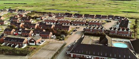 A large, circular cluster of red-brick houses with a central building that includes a swimming pool.