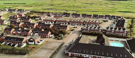 A large, circular cluster of red-brick houses with a central building that includes a swimming pool.