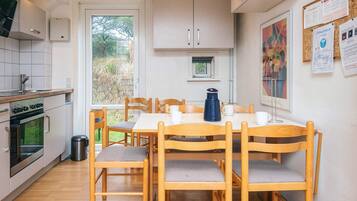 A modern kitchen with wooden cabinets, a dining table with chairs, and a view of the outdoors.