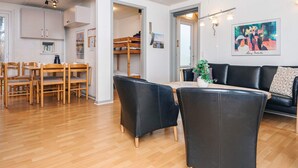 Um espaço moderno para relaxar, com área de refeições, sofá de couro preto e uma beliche.