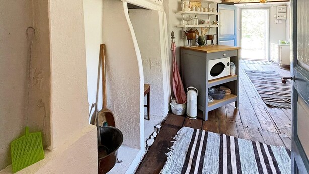 A kitchen with wooden shelves, a microwave, and a wooden door. - 4 Person Holiday Home in Furuby (Hovmantorp)
