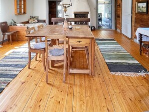 A wooden dining table with chairs, a fireplace, and a view of the outdoors. - 4 Person Holiday Home in Furuby (Hovmantorp)