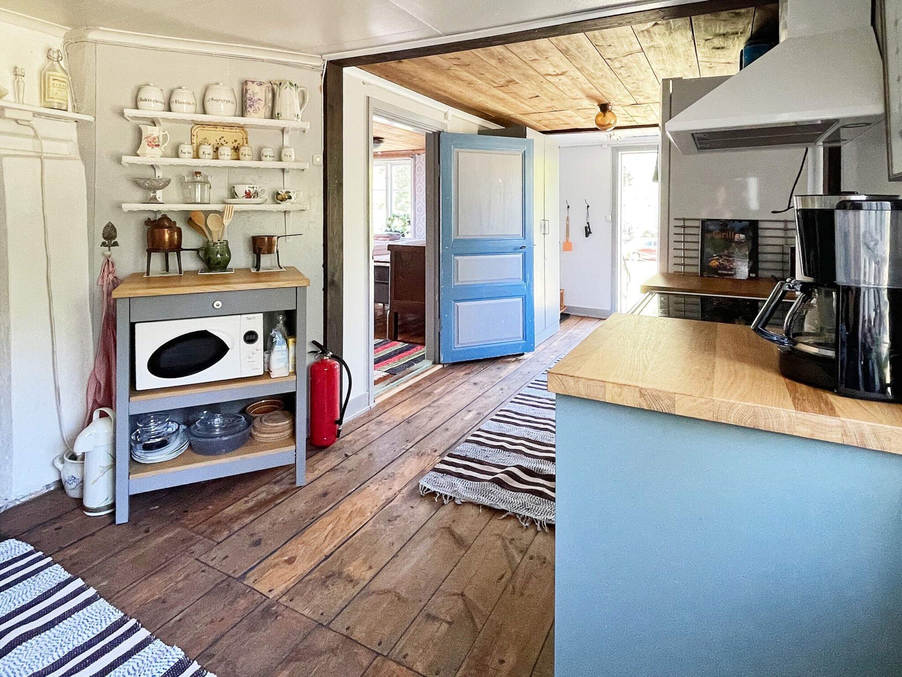 A kitchen with wooden flooring, a coffee maker, and a fire extinguisher.