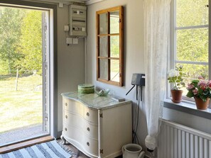 A room with a white dresser, a mirror, a window with a view of greenery, and a power outlet on the wall. - 4 Person Holiday Home in Furuby (Hovmantorp)