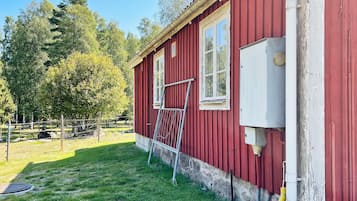A red building with a window and a ladder leaning against it.