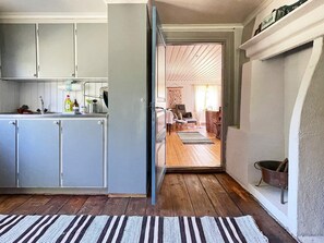 A kitchen with grey cabinets, a sink, and a striped rug leading to a dining area with a table and chairs. - 4 Person Holiday Home in Furuby (Hovmantorp)