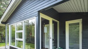 Una casa con porche cubierto, ventanas amplias y puerta con panel de vidrio.