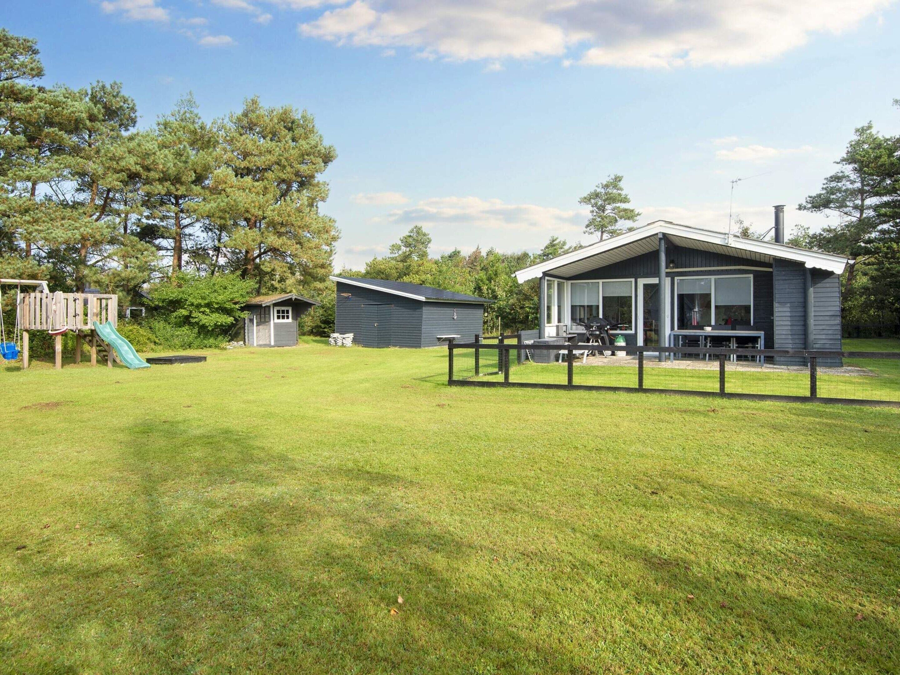 A residential property with a fenced yard, a play area, and a house with a covered patio.