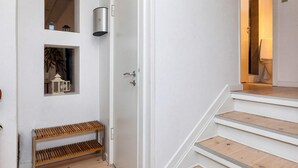 A staircase with wooden steps and white walls, leading to a room with a door. - 4 Star Holiday Home in Skagen (Skagen)