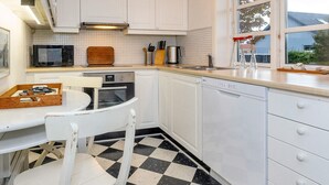 A kitchen with white cabinets, a microwave, an oven, a dishwasher, and a checkered floor. - 4 Star Holiday Home in Skagen (Skagen)