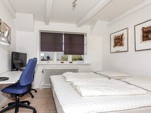 A bedroom with a bed, a desk with a computer, a chair, a radiator, and a window with blinds. - 6 Person Holiday Home in Skagen (Skagen)