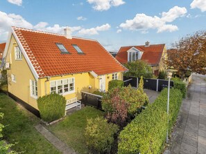 Ein gelbes Haus mit rotem Ziegeldach und einem kleinen Garten.