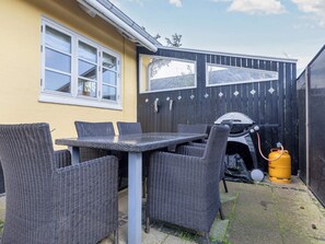Een terras buiten met rieten meubels en een barbecue.