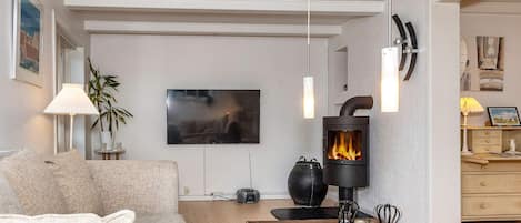 Ein modernes Wohnzimmer mit einer Couch, einem Holztisch, einem Kamin und einem Fernseher.