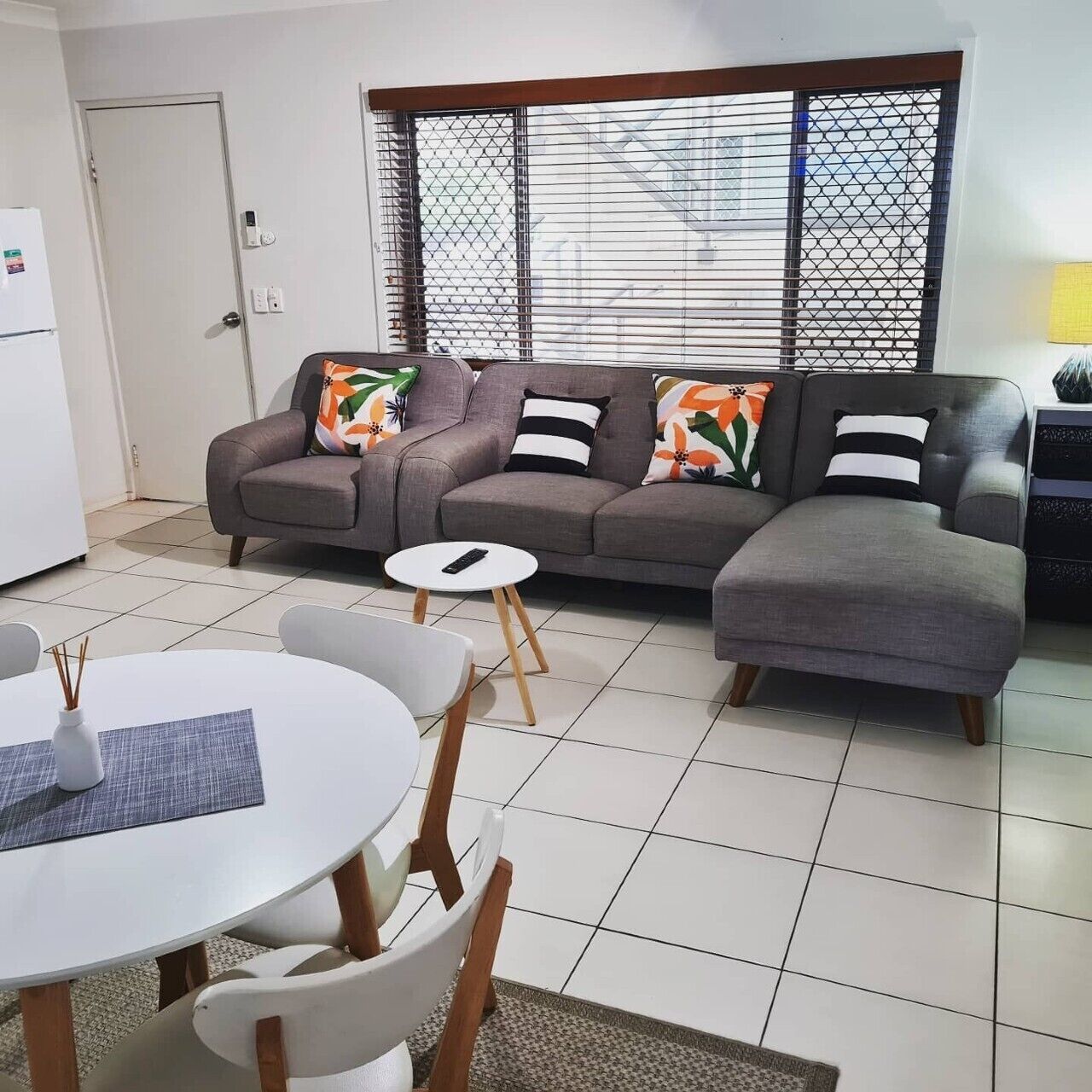Una sala moderna con un sofá seccional gris, una mesita redonda y un comedor con sillas.