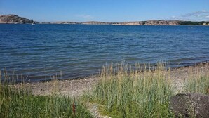Un lago tranquilo con orillas cubiertas de hierba y afloramientos rocosos a lo lejos.
