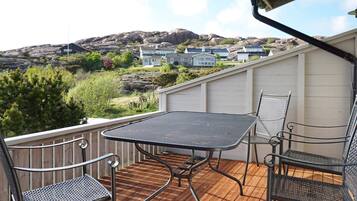 Una terraza al aire libre con una mesa y sillas, con vistas a una zona residencial con casas y colinas.