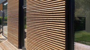 A modern building exterior with horizontal wooden slats and large glass windows.