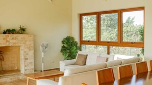 Ein geräumiges Wohnzimmer mit Kamin, großem Fenster, einer Couch und einem Esstisch.