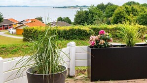 A residential area with a view of a lake, houses, and a garden with a potted plant and flowers. - 6 Person Holiday Home in Aabenraa-by Traum (Aabenraa)