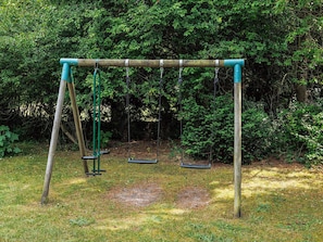 A swing set in a wooded area.