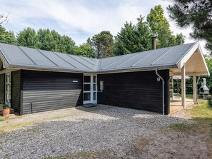 Eine Doppelgarage mit Kiesweg, überdachter Terrasse und Schornstein.