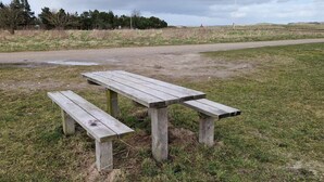 Una mesa de picnic de madera con bancos en un campo cubierto de hierba.