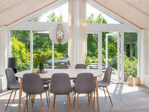 A modern dining area with a round table, six chairs, and a hanging light fixture.