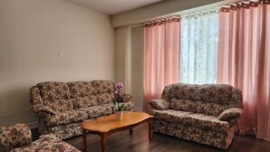 A living room with two floral-patterned sofas, a wooden coffee table, and a potted orchid. - Brand new home in Caledonia walking distance to river trail (Caledonia)