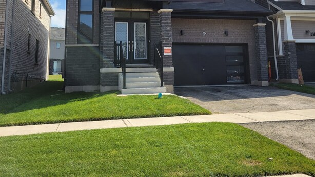 A modern two-story house with a garage, a front porch, and a well-maintained lawn. - Brand new home in Caledonia walking distance to river trail (Caledonia)