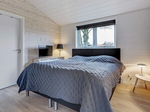 A bedroom with a bed, a TV, a lamp, and a window.