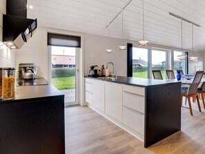 A modern kitchen with a large island, built-in appliances, and a view of the outdoors. - 5 Star Holiday Home in Hejls (Hejls)