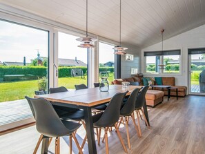 A modern kitchen with a large dining table, black chairs, and a view of the garden. - 5 Star Holiday Home in Hejls (Hejls)