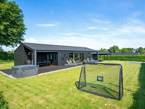 A modern house with a covered patio, outdoor seating, and a fenced yard. - 5 Star Holiday Home in Hejls (Hejls)