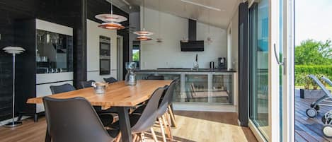 Une cuisine moderne avec un coin repas, de grandes fenêtres et une vue sur l’extérieur.